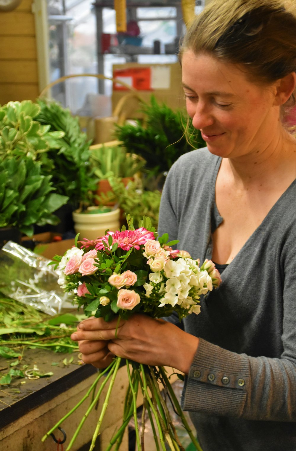 woman wearing gray cardigan holding flower bouquet