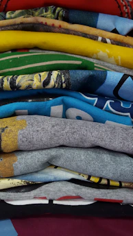 A stack of colorful custom t-shirts neatly folded with a price tag showing a discount.