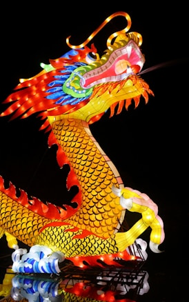 A vibrant and illuminated dragon sculpture, featuring intricate designs and a variety of vivid colors including red, yellow, green, and blue. The dragon has a serpentine body, detailed scales, and an expressive face, exuding a sense of grandeur and mystique.