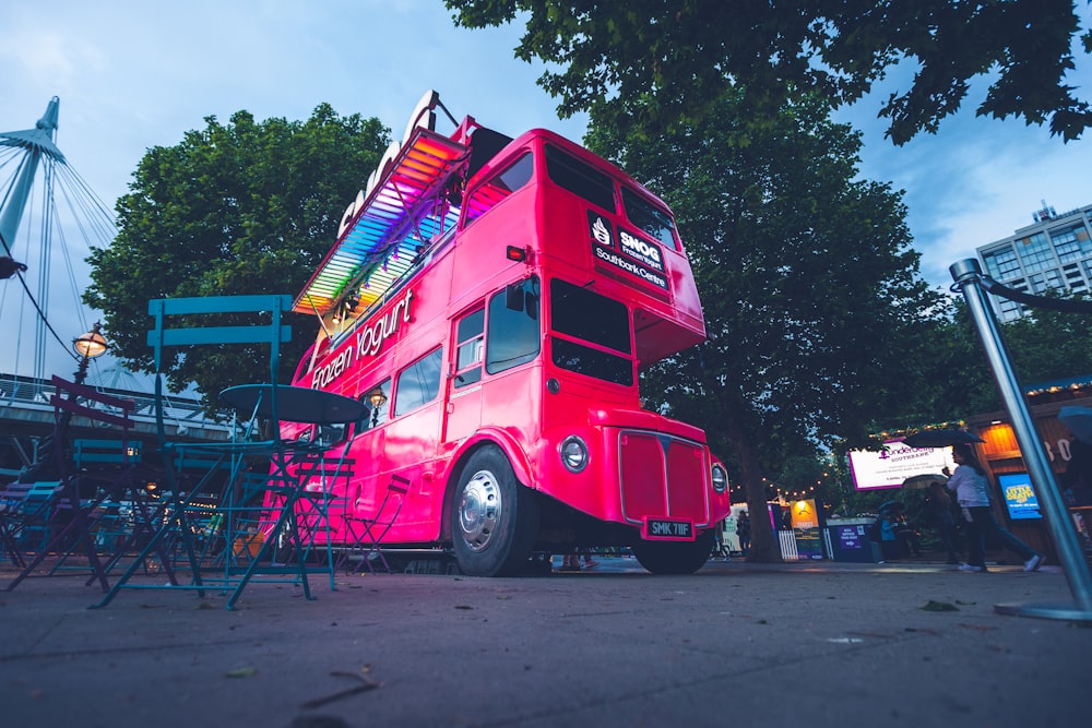 red and black double decker bus near green-leafed trees