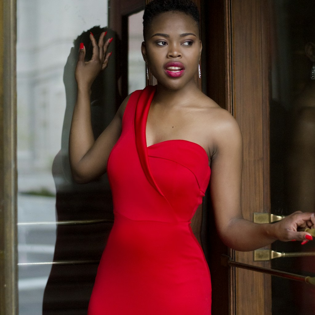 woman wearing red bodycon dress holding glass door
