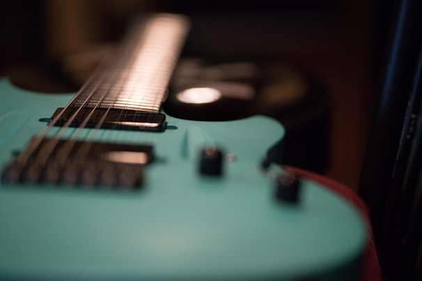An artistic shot of Tuzo Jerome with his guitar in a studio.