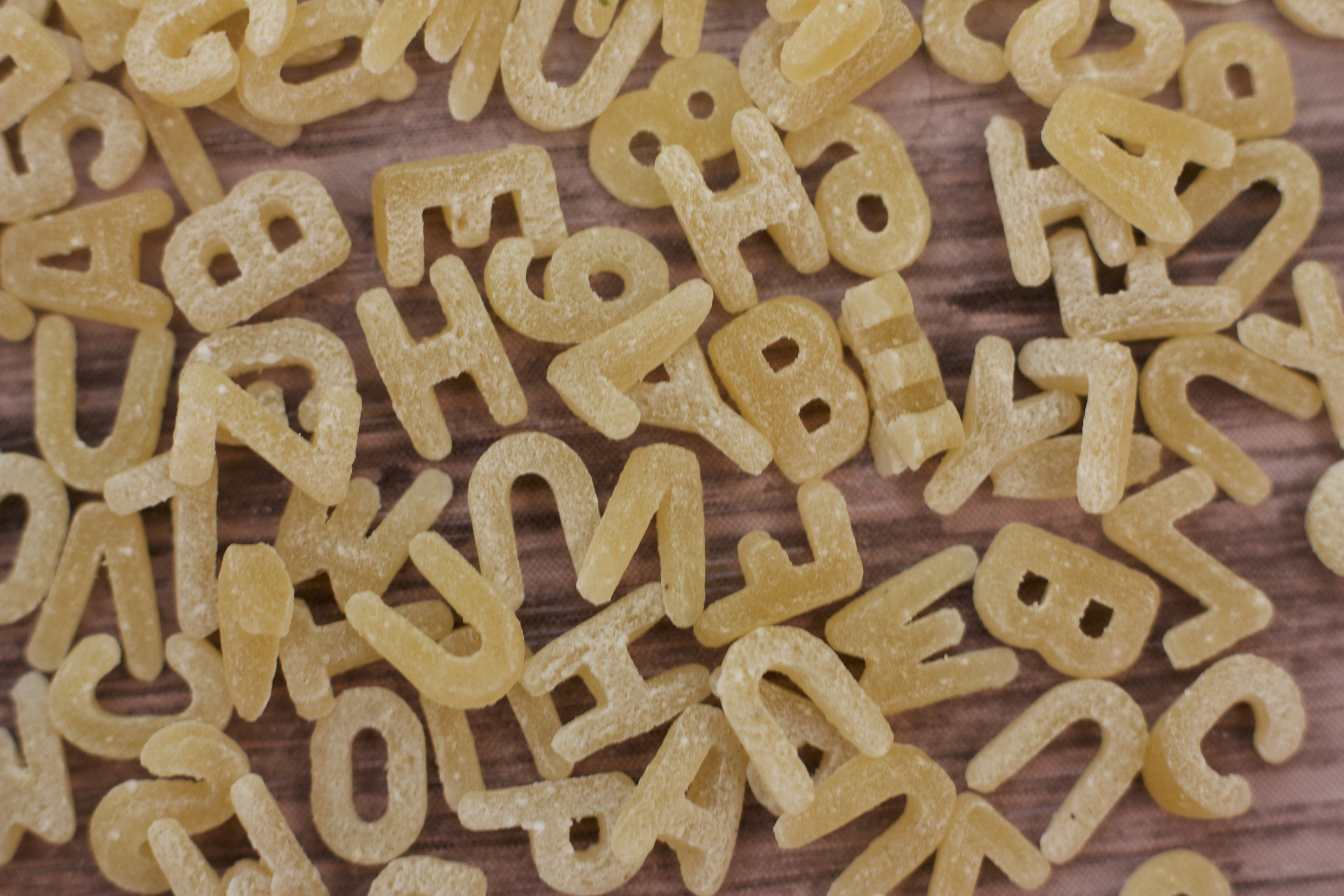 Scattered wooden alphabet letter tiles on a brown wooden surface`