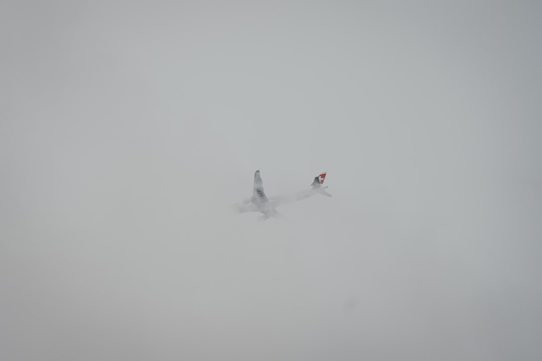 white airliner flying on sky covered fog