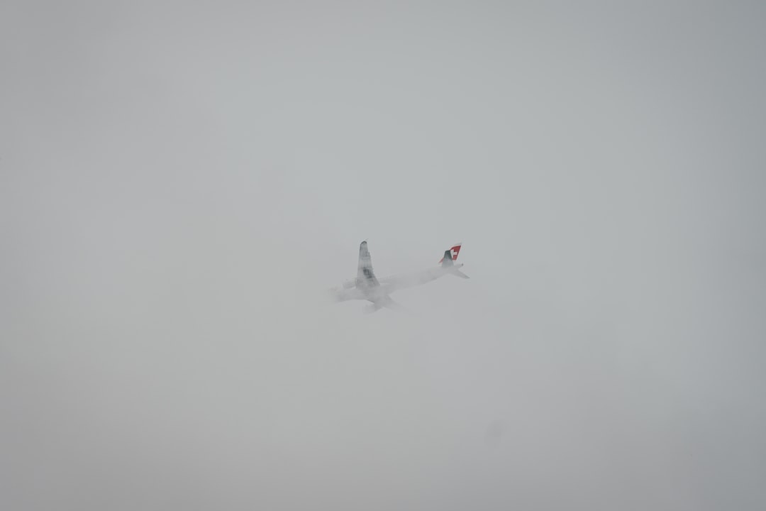 white airliner flying on sky covered fog,