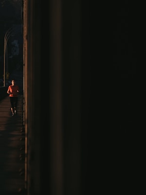 A dynamic runner wearing bright orange and light sea green sportswear sprinting on a track at sunrise.