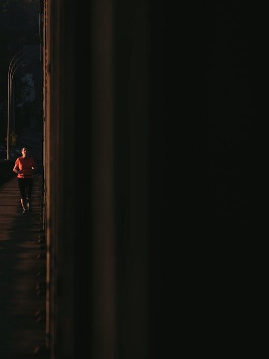 A dynamic runner wearing bright orange and light sea green sportswear sprinting on a track at sunrise.