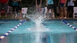 Panoramic view of a swimming event with spectators cheering around the pool.