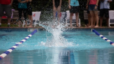 Panoramic view of a swimming event with spectators cheering around the pool.