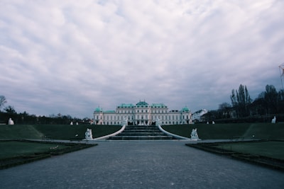 A panoramic view of a sprawling Renaissance palace surrounded by lush gardens.