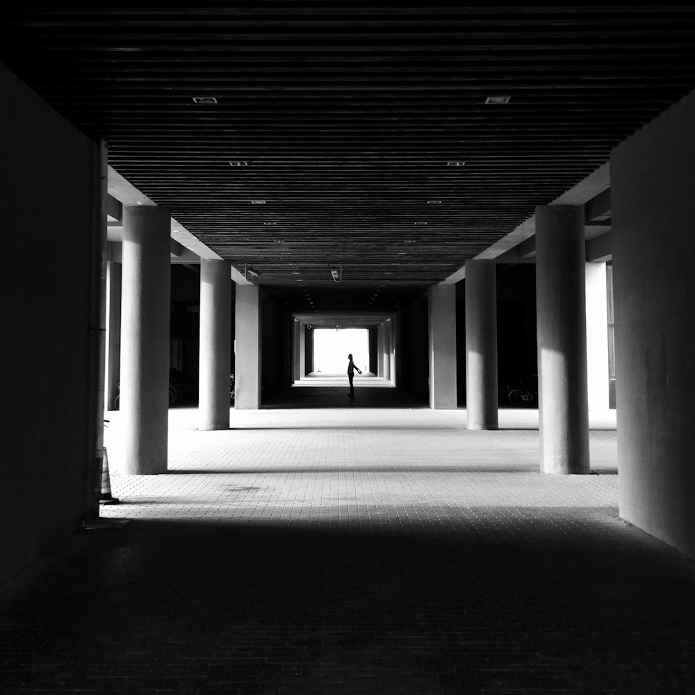 grayscale photo of person standing inside building