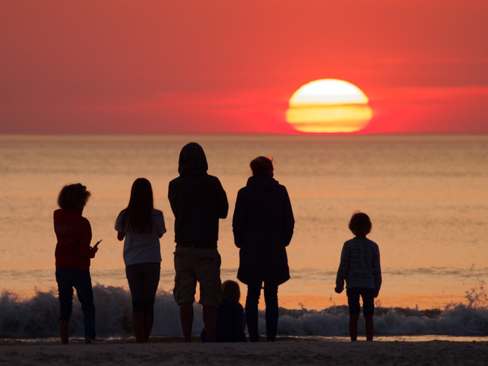 silhouette photography of people facing ocean during golden hour