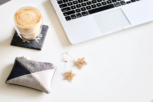 A cozy workspace with a laptop open to a fashion blog, surrounded by skincare products and a cup of tea.