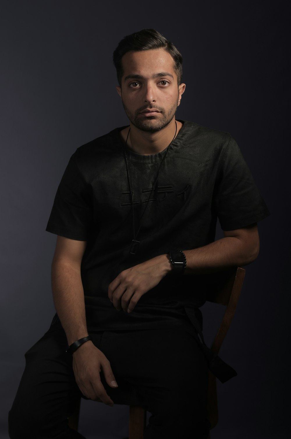 man in black shirt sitting on wooden chair