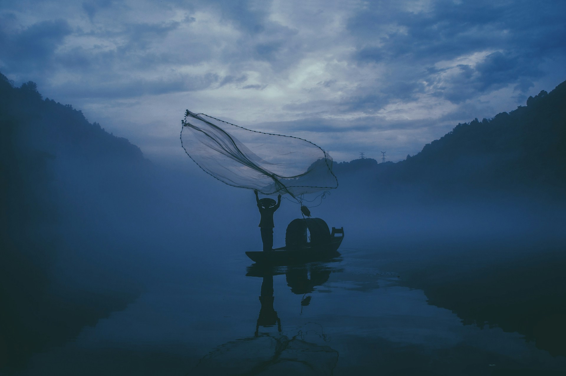 person fishing in a body of water during nightime