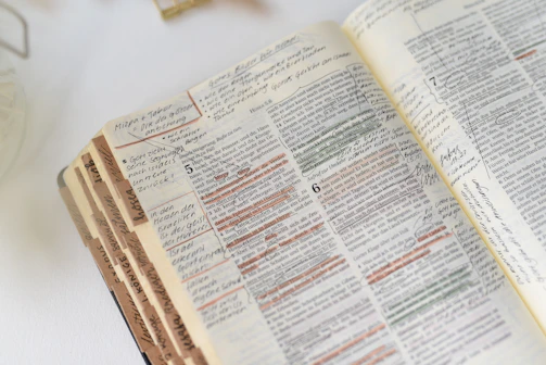 Close-up of an open Bible with highlighted passages and notes.