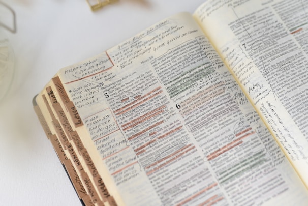 A close-up of someone highlighting passages in a thick, well-read book.