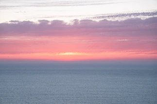 A serene ocean horizon at sunset reflecting deep blues and aqua hues.