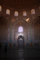 Close-up of skilled hands installing intricate tile work in a mosque interior.