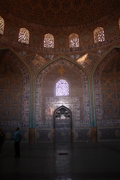 Close-up of skilled hands installing intricate tile work in a mosque interior.