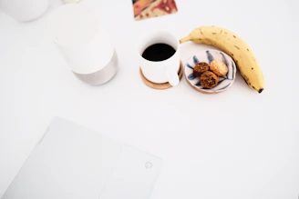 A minimalist desk showing profiles of food creators on a screen alongside notes and a cup of coffee.