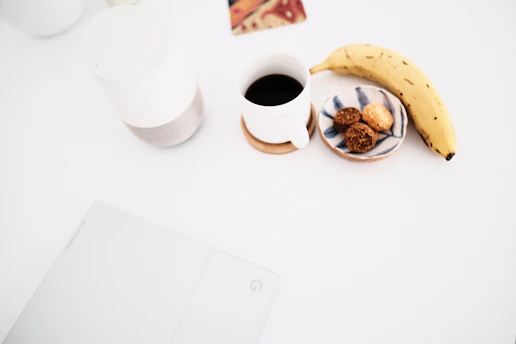 A minimalist desk showing profiles of food creators on a screen alongside notes and a cup of coffee.