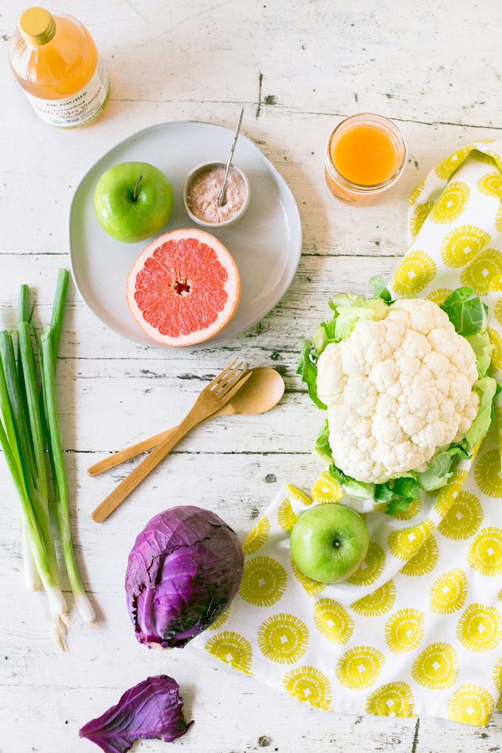 green apple, sliced of grapefruit with purple cabbage, scallions and cauliflower on table