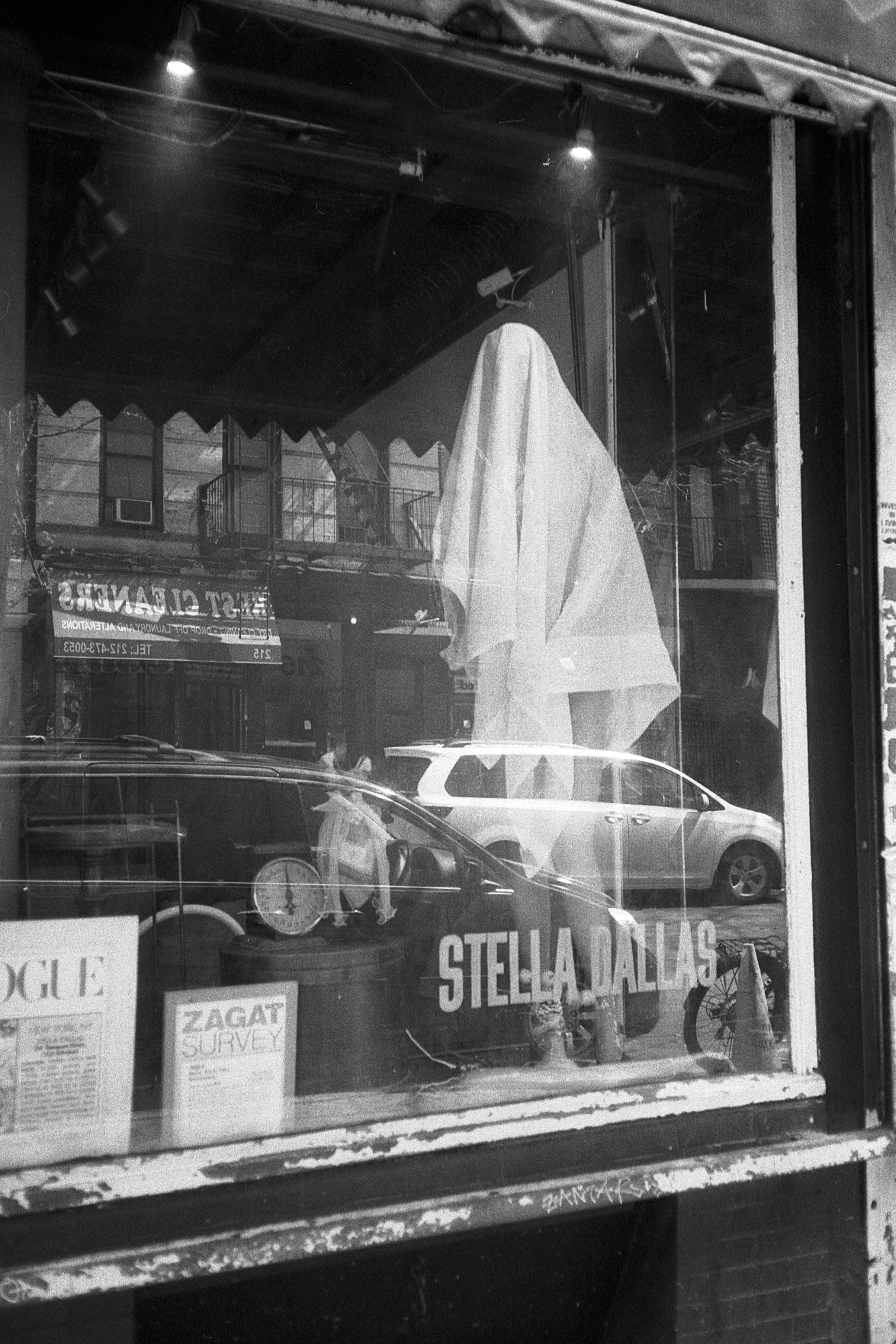 Photo en niveaux de gris de la devanture d’un magasin reflétant des véhicules