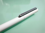 Close-up of a sleek branded pen resting on a clean white desk.