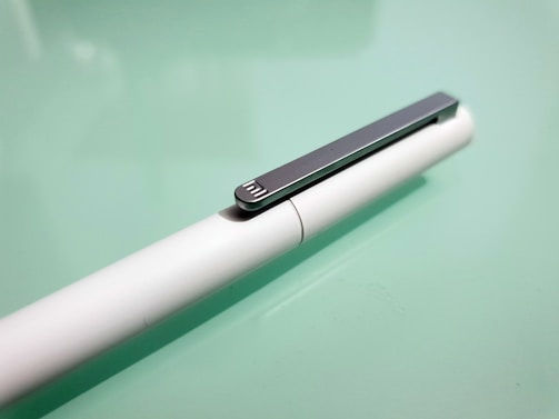 Close-up of a sleek padbergpen with a polished metal clip resting on a wooden desk.