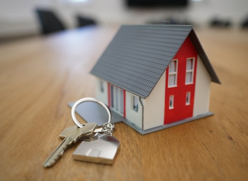 white and red wooden house miniature on brown table