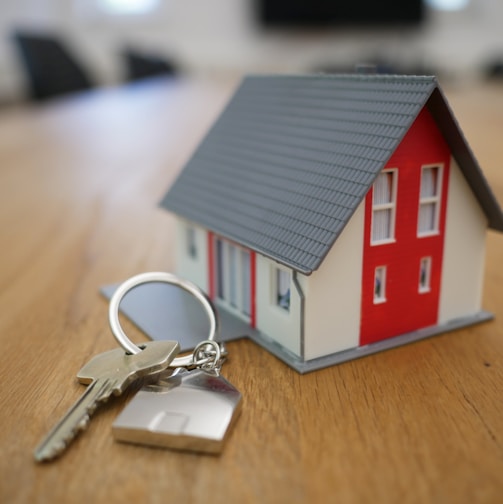 white and red wooden house miniature on brown table