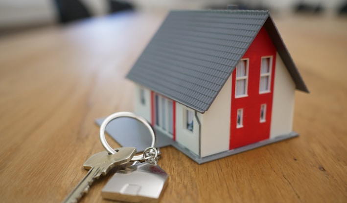 white and red wooden house miniature on brown table