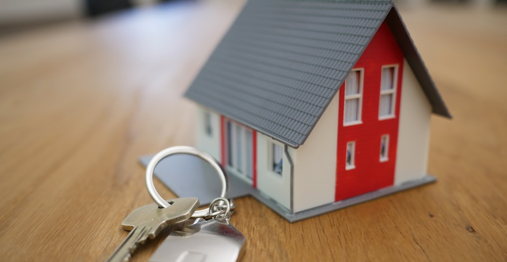 white and red wooden house miniature on brown table