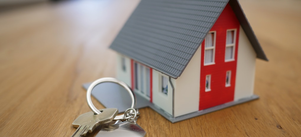 white and red wooden house miniature on brown table