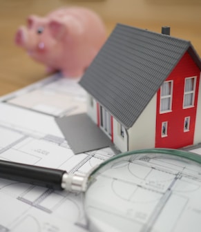 white and red wooden house beside grey framed magnifying glass