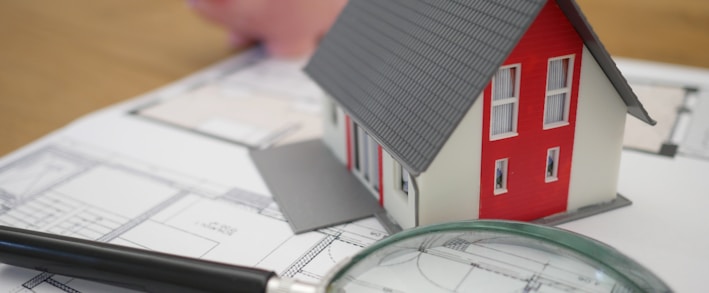 white and red wooden house beside grey framed magnifying glass