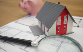 white and red wooden house beside grey framed magnifying glass