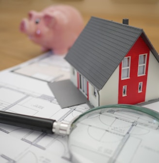 white and red wooden house beside grey framed magnifying glass