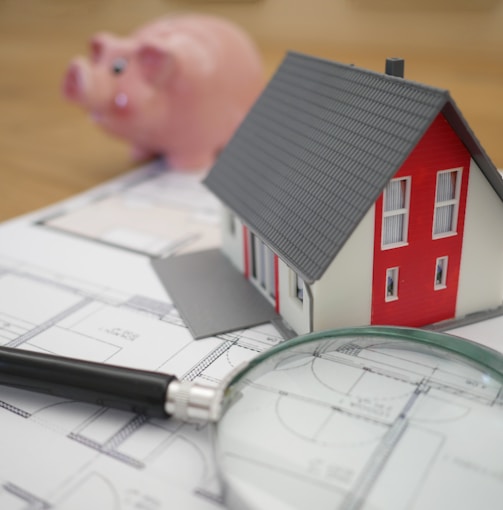 white and red wooden house beside grey framed magnifying glass