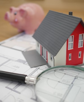 white and red wooden house beside grey framed magnifying glass