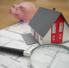 white and red wooden house beside grey framed magnifying glass