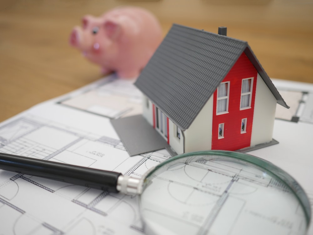 Maison en bois blanc et rouge à côté d’une loupe à cadre gris