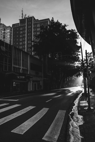 A cinematic black-and-white photo capturing a quiet street at dawn, blending urban life and tranquil moments.
