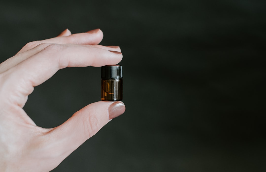 person holding small brown tinted glass bottle