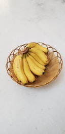 bunch of yellow bananas in a brown wicker bowl