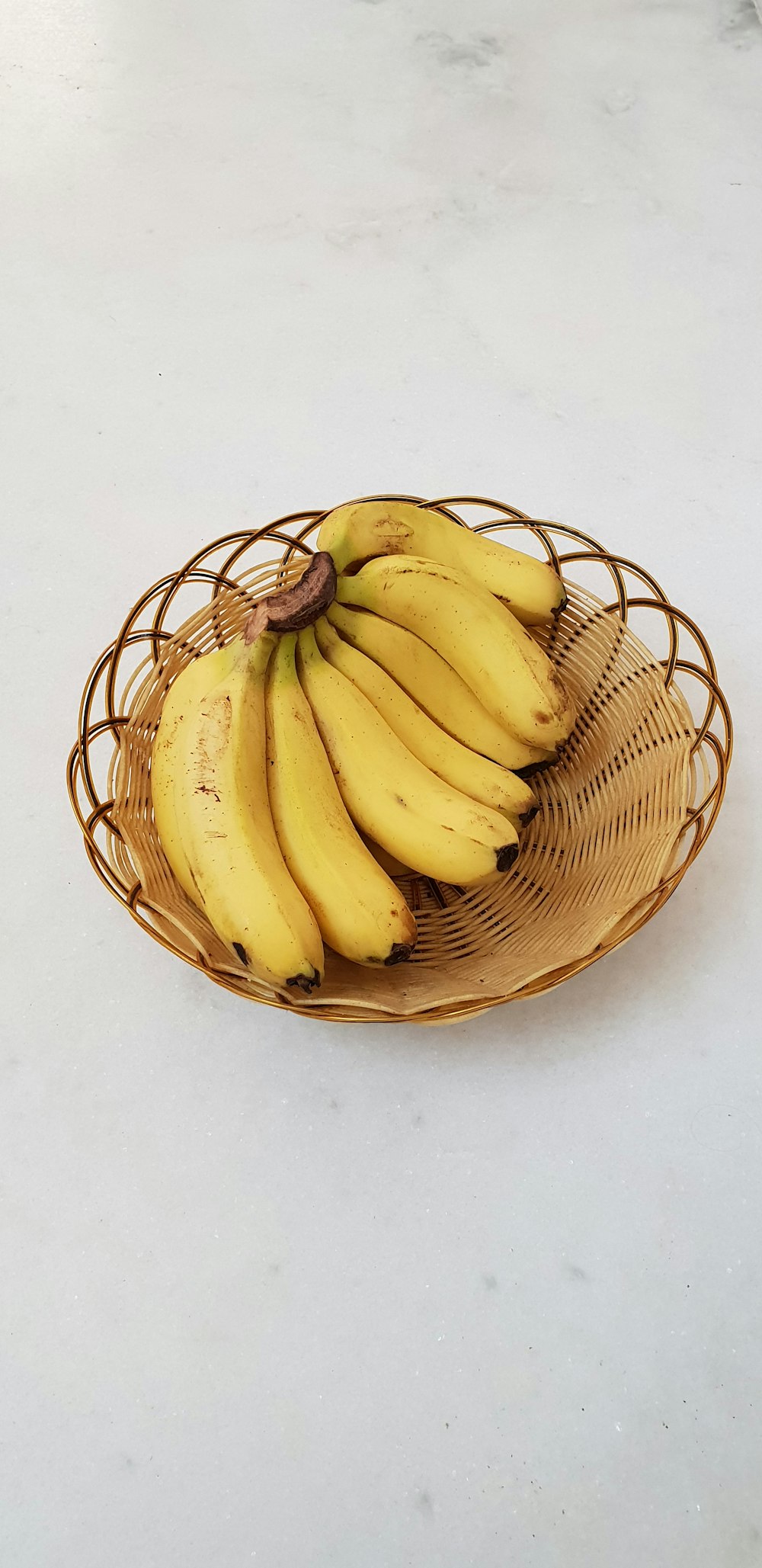 bunch of yellow bananas in a brown wicker bowl