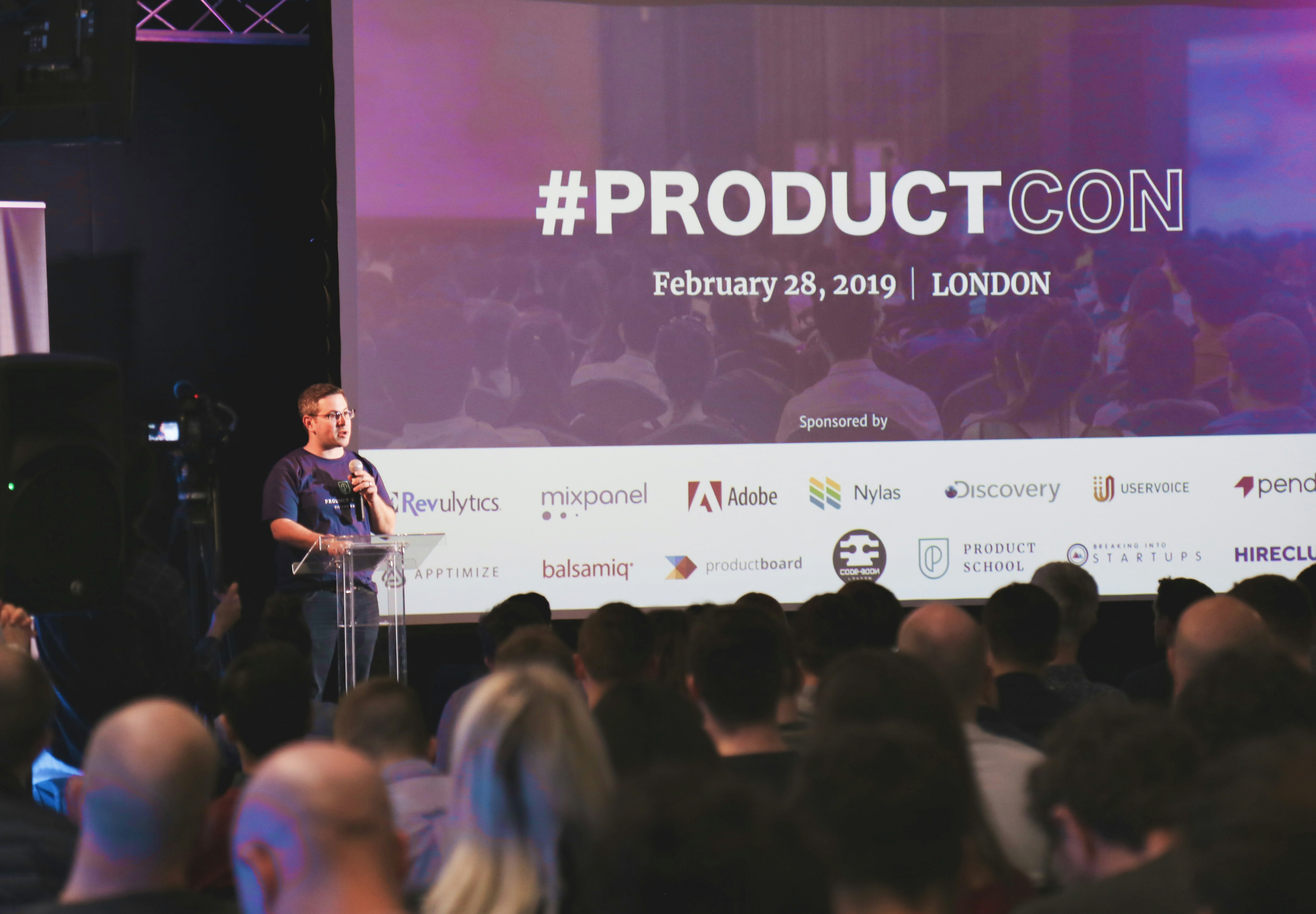 a man standing on stage behind a podium giving a presentation at an event