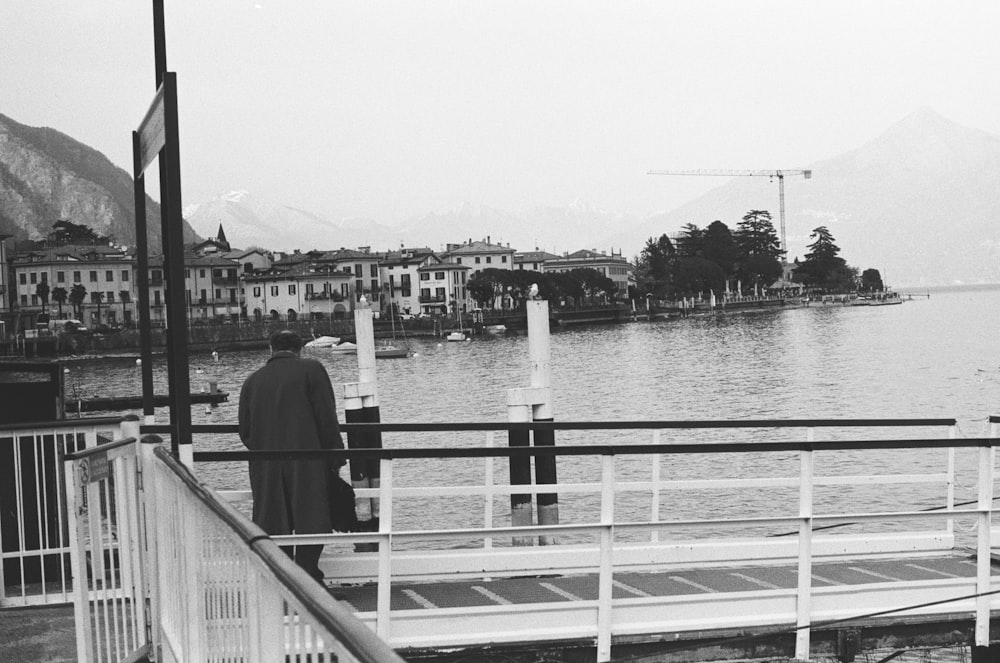 person standing beside a body of water gray-scale photography