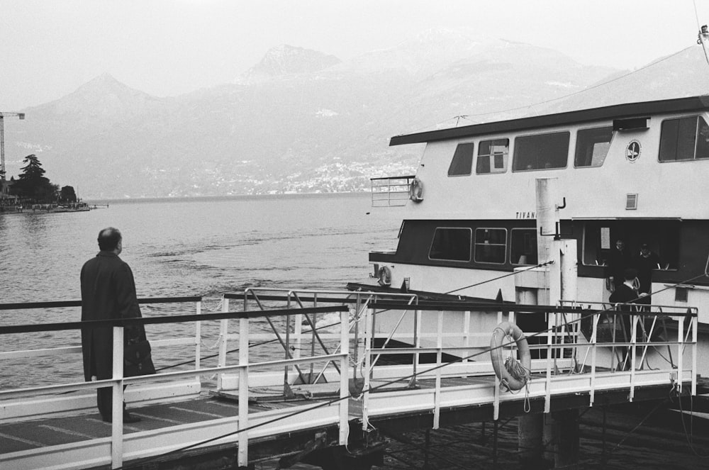 grayscale photo of man on dock